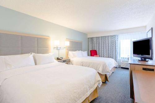a hotel room with two beds and a flat screen tv at Hampton Inn Rochester in Rochester