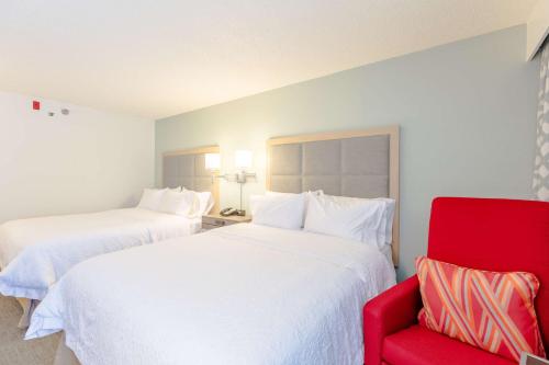 a hotel room with two beds and a red chair at Hampton Inn Rochester in Rochester