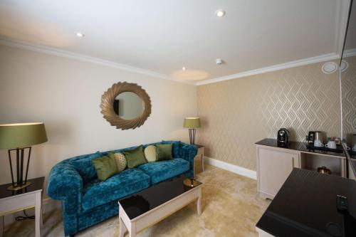 a living room with a blue couch and a mirror at Best Western Abbots Barton Hotel in Canterbury