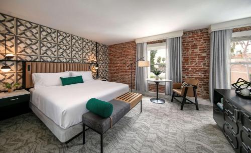 a bedroom with a large bed and a brick wall at Hotel Virginia Santa Barbara, Tapestry Collection by Hilton in Santa Barbara