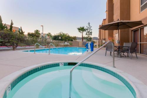 a swimming pool with a table and an umbrella at Hampton Inn San Marcos in San Marcos