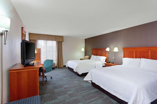 a hotel room with two beds and a flat screen tv at Hampton Inn San Marcos in San Marcos