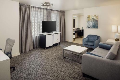 a living room with a couch and a tv in a hotel room at DoubleTree Suites by Hilton Hotel Detroit Downtown - Fort Shelby in Detroit