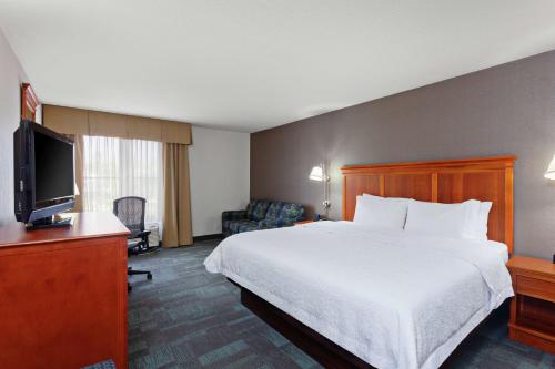 a hotel room with a bed and a flat screen tv at Hampton Inn San Marcos in San Marcos