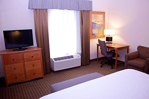 a hotel room with a bed and a television and a desk at Hampton Inn Sidney in Sidney