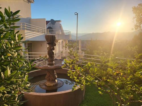 a fountain in front of a building with the sun shining at Apartments Šofranac in Podgorica