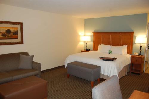 um quarto de hotel com uma cama e uma cadeira em Hampton Inn Sidney em Sidney