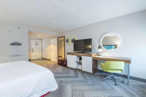 a hotel room with a bed and a desk and a mirror at Hampton Inn Tampa-Veterans Expressway in Tampa