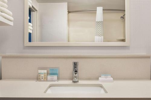 W łazience znajduje się umywalka i lustro. w obiekcie Hampton Inn London Ontario w mieście London