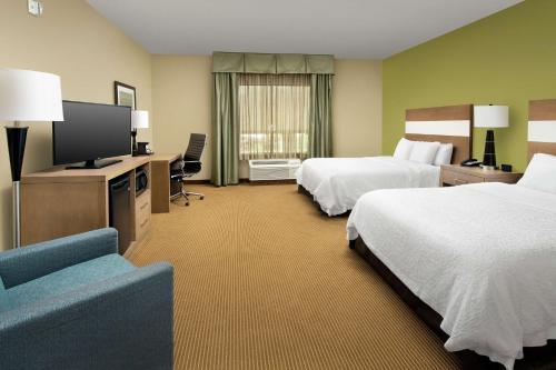 a hotel room with two beds and a flat screen tv at Hampton Inn Lake Charles in Lake Charles