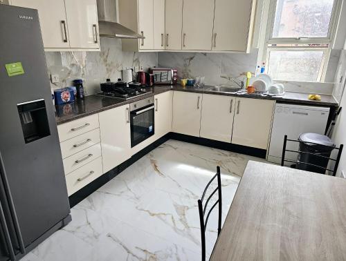 a kitchen with white cabinets and a marble floor at The Private Rooms in Paddington in London