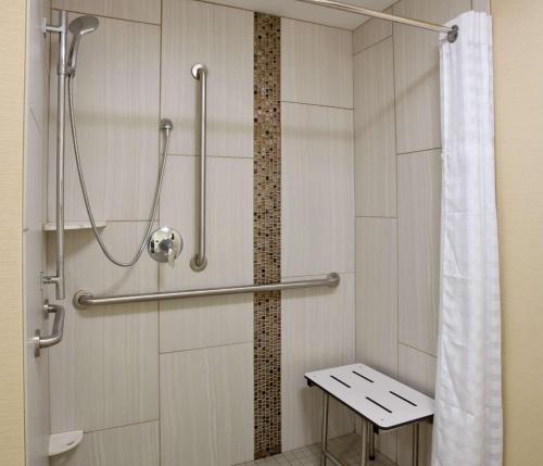 a bathroom with a shower with a bench in it at Homewood Suites Davenport in Bettendorf