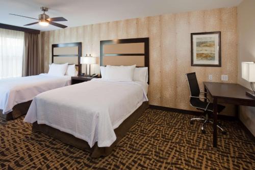 ein Hotelzimmer mit 2 Betten und einem Schreibtisch in der Unterkunft Homewood Suites Davenport in Bettendorf
