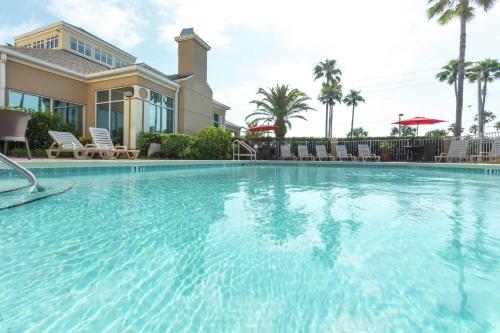 a large swimming pool in front of a house at Hilton Garden Inn Saint Augustine Beach in Saint Augustine Beach