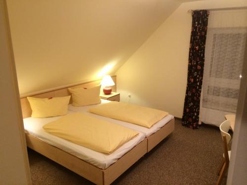 a bedroom with a bed with white sheets and a window at Hotel zur Heideblüte in Hambühren