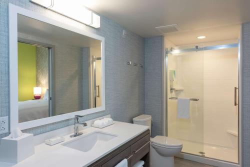 a bathroom with a sink and a toilet and a mirror at Home2 Suites By Hilton Indianapolis Airport in Indianapolis