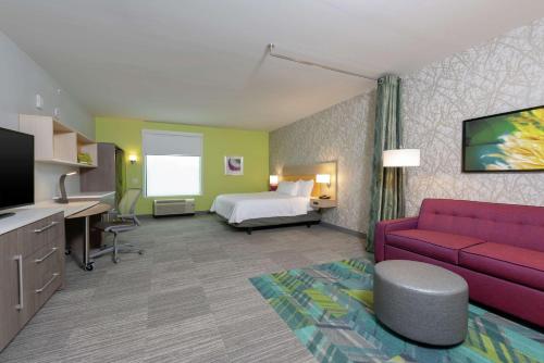 a hotel room with a bed and a couch at Home2 Suites By Hilton Indianapolis Airport in Indianapolis