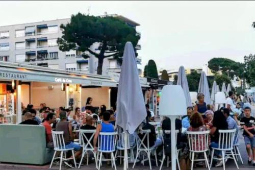 Un groupe de personnes assises à des tables avec des parapluies dans l'établissement Oasis Marin 1 Studio Proche Mer Parking wifi, à Cagnes-sur-Mer
