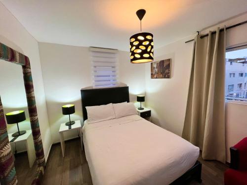 1 dormitorio con cama blanca y lámpara colgante en CUADRUPLEX Con TERRAZA, en Lima