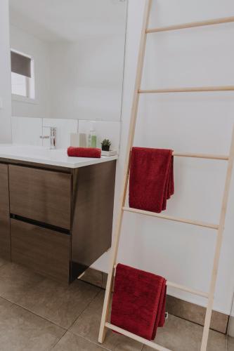a bathroom with two red towels on a ladder at Meadowbank Lakehouse in Ellendale