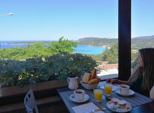 a woman is sitting at a table with a tableasonable at Hotel & Restaurant le Saint Jean in Cargèse