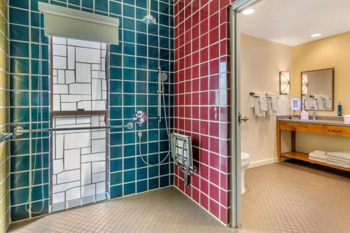 y baño con ducha y paredes de azulejos rojos y azules. en Hilton Grand Vacations Club Palm Desert en Palm Desert
