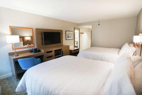 a hotel room with two beds and a desk with a television at Hampton Inn Clarks Summit in Clarks Summit