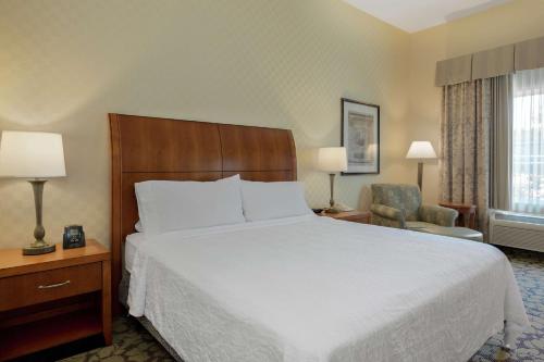 a hotel room with a bed and a chair at Hilton Garden Inn Sacramento Elk Grove in Elk Grove