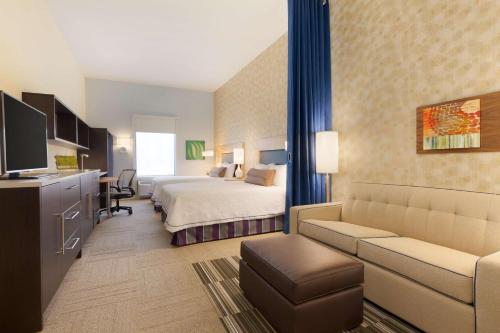 オクラホマシティにあるHome2 Suites by Hilton Oklahoma City Southのベッドとソファ付きのホテルルーム
