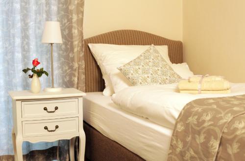 ein Schlafzimmer mit einem Bett und einem Nachttisch mit einem weißen Bett in der Unterkunft Haus Geistmeier in Lippstadt