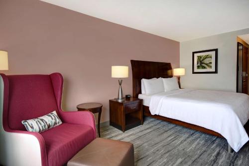 a hotel room with a bed and a chair at Hilton Garden Inn Fort Myers in Fort Myers