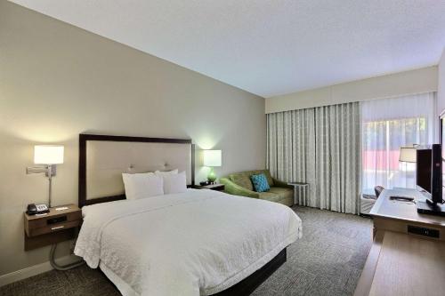 a hotel room with a large bed and a chair at Hampton Inn Savannah-I-95/Richmond Hill in Richmond Hill