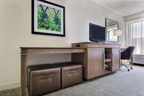 a room with a desk with a television and a chair at Hampton Inn Savannah-I-95/Richmond Hill in Richmond Hill