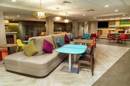 a living room with a couch and tables and chairs at Home2 Suites By Hilton Roseville Sacramento in Roseville