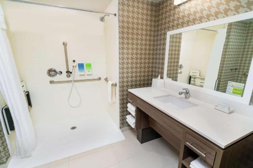 a bathroom with a sink and a tub and a mirror at Home2 Suites By Hilton Roseville Sacramento in Roseville