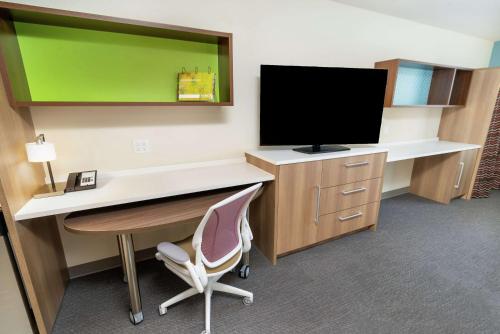 a room with a desk with a television and a chair at Home2 Suites By Hilton Roseville Sacramento in Roseville
