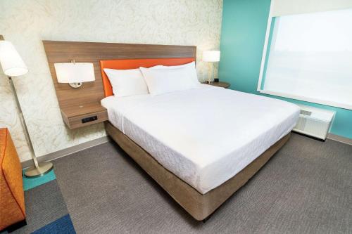 a bedroom with a large bed with an orange headboard at Home2 Suites By Hilton Roseville Sacramento in Roseville