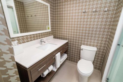 a bathroom with a toilet and a sink and a mirror at Home2 Suites By Hilton Roseville Sacramento in Roseville