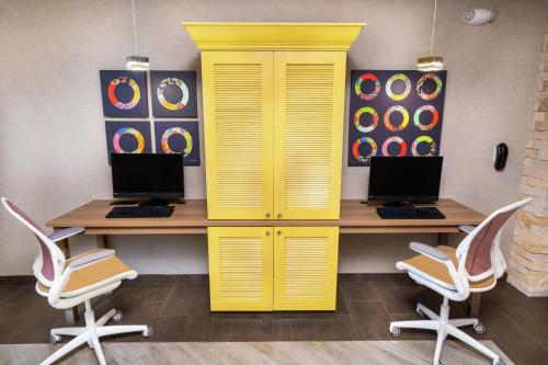 a yellow desk with two computers on top of it at Home2 Suites By Hilton Roseville Sacramento in Roseville