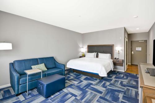 a hotel room with a bed and a blue couch at Hampton Inn Kyle in Kyle