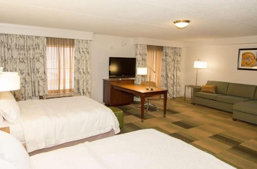 a hotel room with a bed and a couch and a television at Hampton Inn & Suites Albany-Downtown in Albany
