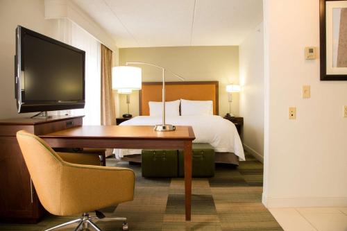 アルバニーにあるハンプトン イン & スイーツ アルバニー ダウンタウンのベッド、デスク、テレビが備わるホテルルームです。