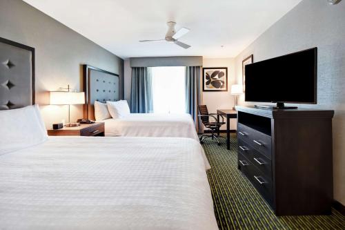 a hotel room with two beds and a flat screen tv at Homewood Suites by Hilton Novi Detroit in Novi