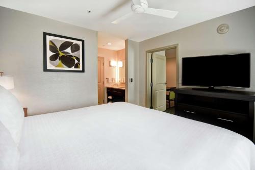 a bedroom with a white bed and a flat screen tv at Homewood Suites by Hilton Novi Detroit in Novi
