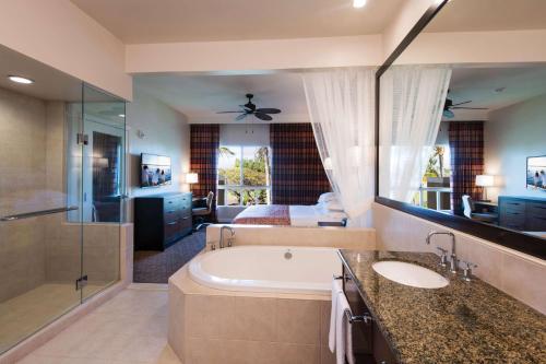 a bathroom with a tub and a large mirror at Hilton Grand Vacations Club Kohala Suites Waikoloa in Waikoloa