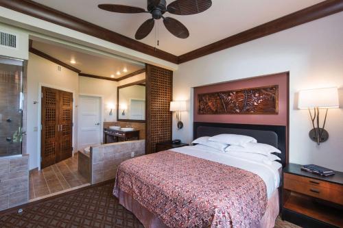 a bedroom with a large bed and a bathroom at Hilton Grand Vacations Club Kohala Suites Waikoloa in Waikoloa