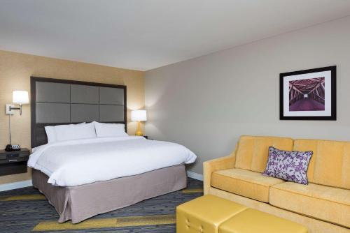 Hampton Inn & Suites West Lafayette, In في ويست لافاييت: غرفه فندقيه بسرير واريكه