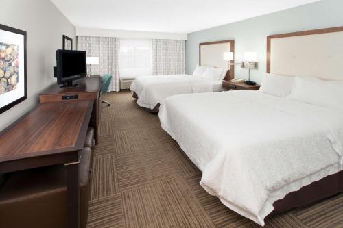 a hotel room with two beds and a flat screen tv at Hampton Inn Birch Run in Birch Run