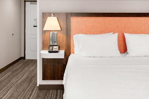 a bedroom with a bed and a night stand with a lamp at Hampton Inn & Suites Burlington in Burlington