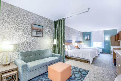 Habitación de hotel con cama y sofá azul en Home2 Suites By Hilton Daphne Spanish Fort, en Daphne